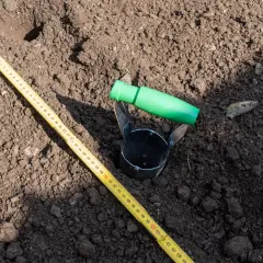 Przyrząd do pobierania próbek gleby i miarka leżą na ziemi. To część badania geotechnicznego gruntu, które pomoże określić jego cenę.