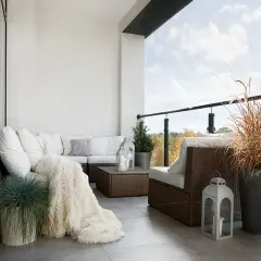 Przytulna loggia z rattanowymi meblami, miękkim kocem i ozdobnymi latarniami. Idealne miejsce na relaks.