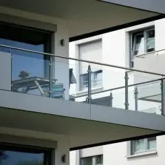 Nowoczesny balkon loggia z przeszkloną balustradą, na którym stoi stolik i krzesła.