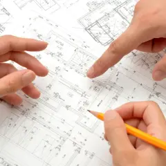 Dłonie analizują plany architektoniczne, wskazując na szczegóły dotyczące metrażu mieszkania i rozmieszczenia pomieszczeń.
