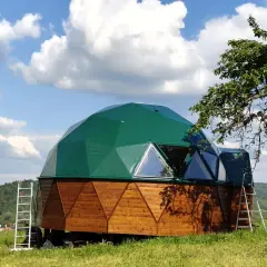 Zielony dom kopułowy z drewnianą podstawą, gotowy do zamieszkania. Sprawdź dom kopułowy pod klucz cena.
