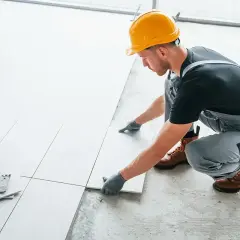 Fachowiec układa płytki na balkonie. Dowiedz się, ile kosztuje położenie płytek na balkonie i jakie materiały są potrzebne.