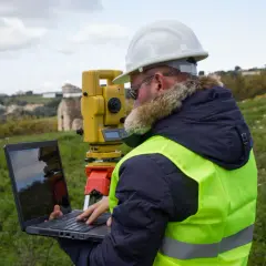 Geodeta z laptopem i tachimetrem w terenie. Sprawdza ponowne wytyczenie granic działki cena.