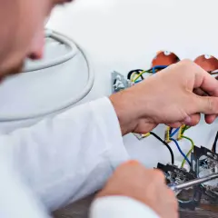 Elektryk podłącza przewody. Zastanawiasz się, ile kosztuje wymiana instalacji elektrycznej? Sprawdź!