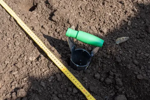 Przyrząd do pobierania próbek gleby i miarka leżą na ziemi. To część badania geotechnicznego gruntu, które pomoże określić jego cenę.