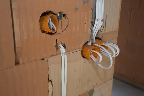 Instalacja elektryczna w trakcie budowy. Widoczne puszki instalacyjne i przewody. Sprawdź nasz cennik usług elektrycznych.