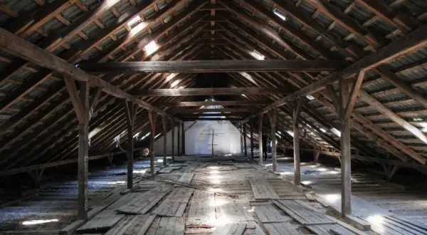 Drewniane poddasze 80m2, gotowe do adaptacji. Widok na konstrukcję dachu i deski podłogowe.