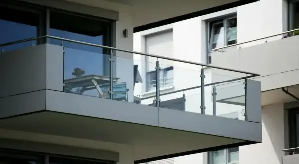 Nowoczesny balkon loggia z przeszkloną balustradą, na którym stoi stolik i krzesła.
