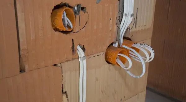 Instalacja elektryczna w trakcie budowy. Widoczne puszki instalacyjne i przewody. Sprawdź nasz cennik usług elektrycznych.