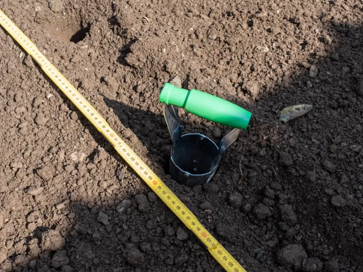 Przyrząd do pobierania próbek gleby i miarka leżą na ziemi. To część badania geotechnicznego gruntu, które pomoże określić jego cenę.