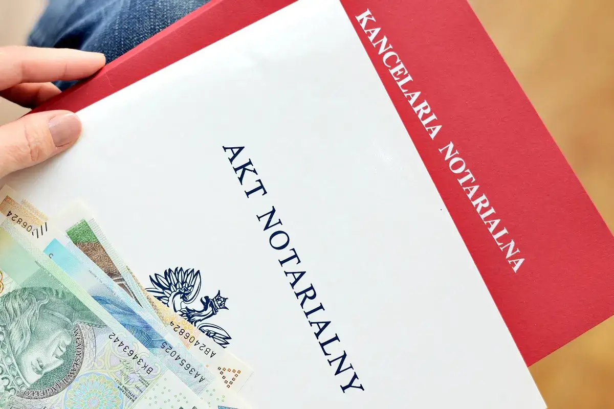 Akt notarialny i polskie banknoty. Dokument z kancelarii notarialnej, który może dotyczyć np. umowy deweloperskiej.