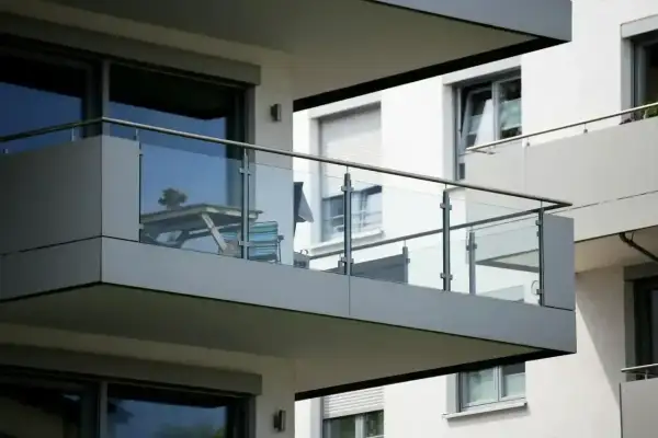 Nowoczesny balkon loggia z przeszkloną balustradą, na którym stoi stolik i krzesła.