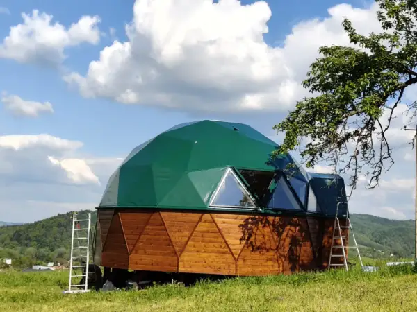 Zielony dom kopułowy z drewnianą podstawą, gotowy do zamieszkania. Sprawdź dom kopułowy pod klucz cena.