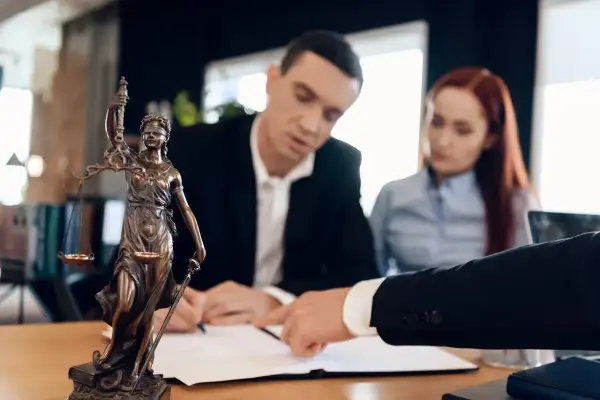Para prawnicza omawia dokumenty, być może związane z eksmisją. Statuetka Temidy symbolizuje sprawiedliwość.